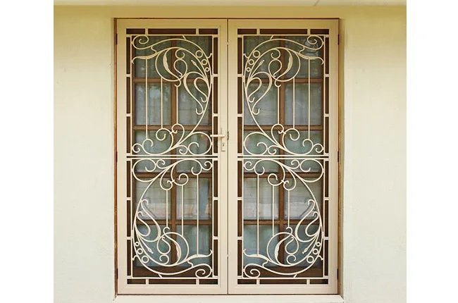 Pair of cream decorative cast security screen doors with a scroll pattern over timber windows